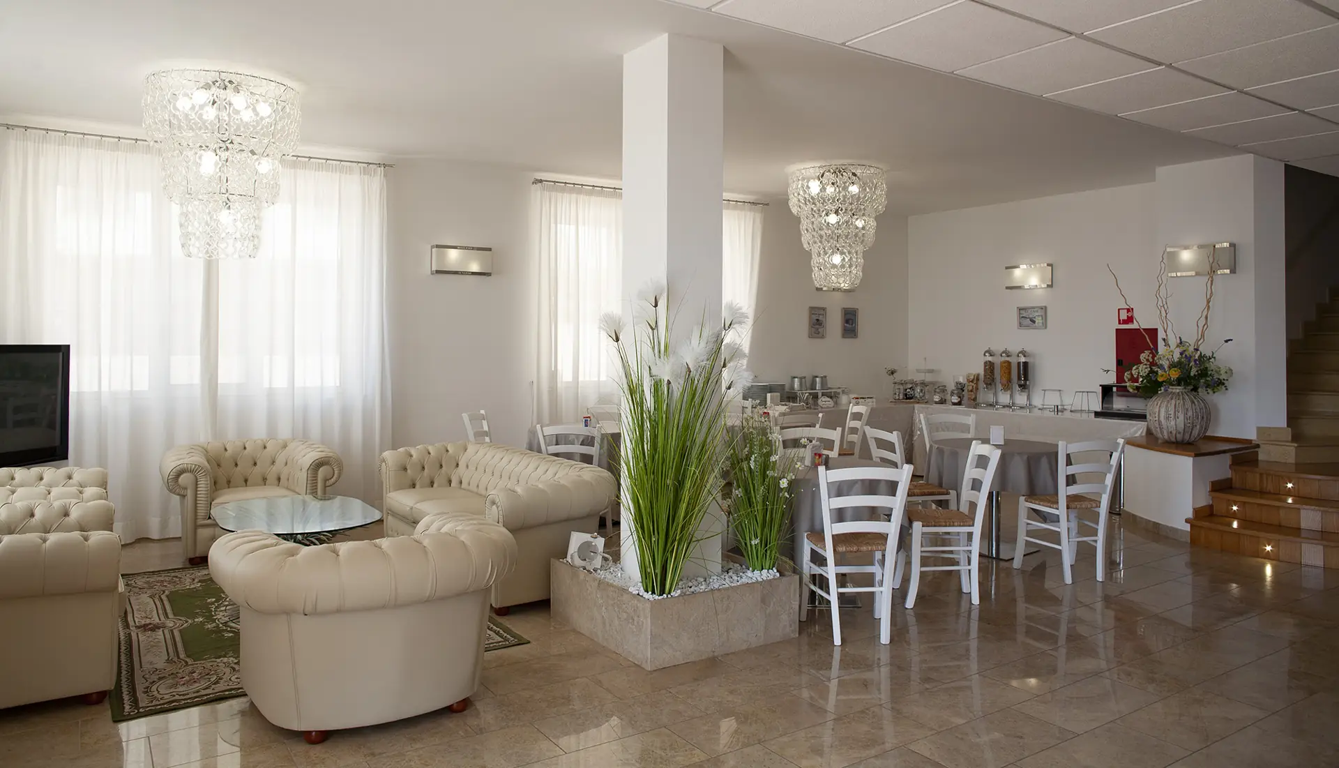 La hall dell’Hotel Di Nardo con divano chiaro, pianta centrale e lampadario